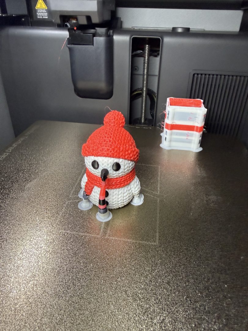 Wielomateriałowy wydruk 3D bałwanka z TPU i PLA na stole roboczym drukarki