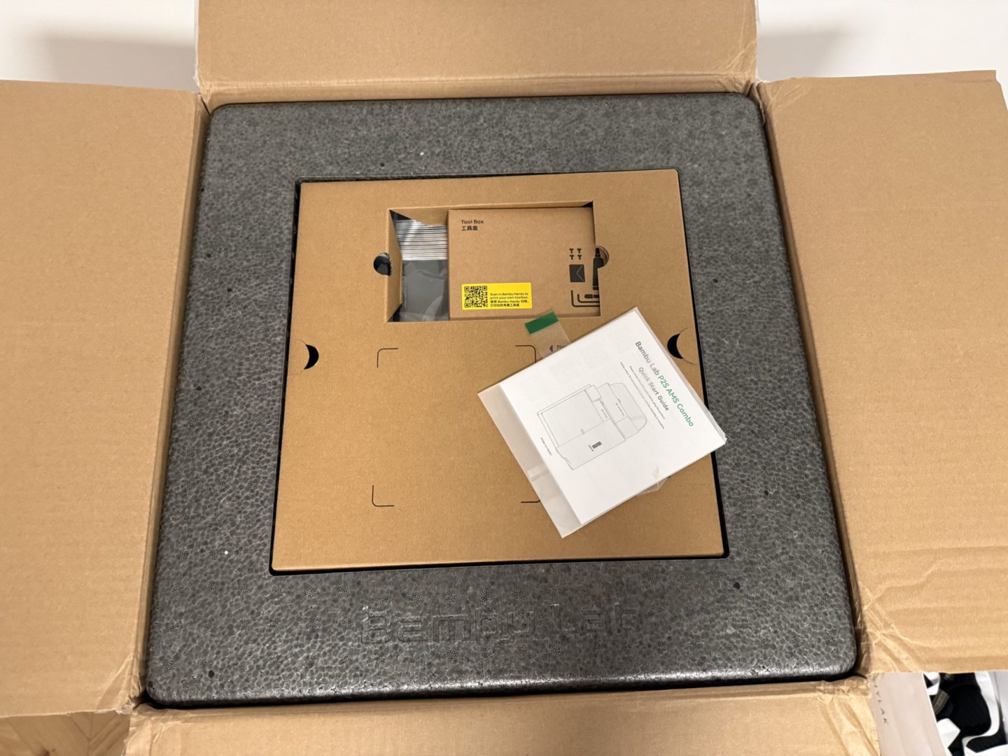 Dokumentacja i akcesoria drukarki 3D Bambu Lab P2S umieszczone w górnej części opakowania